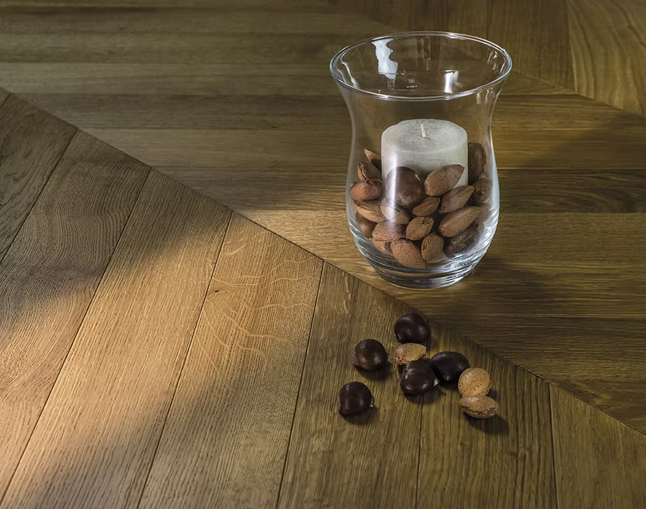 Vaso di vetro con candela bianca e noci su un tavolo di legno, con noci sparse davanti.