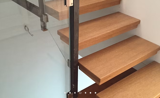 Scala in legno con ringhiera in metallo scuro su pavimento piastrellato chiaro all'interno