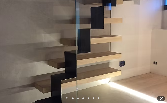 Scala moderna sospesa con gradini scuri e una luce soffusa a pavimento in una stanza minimalista