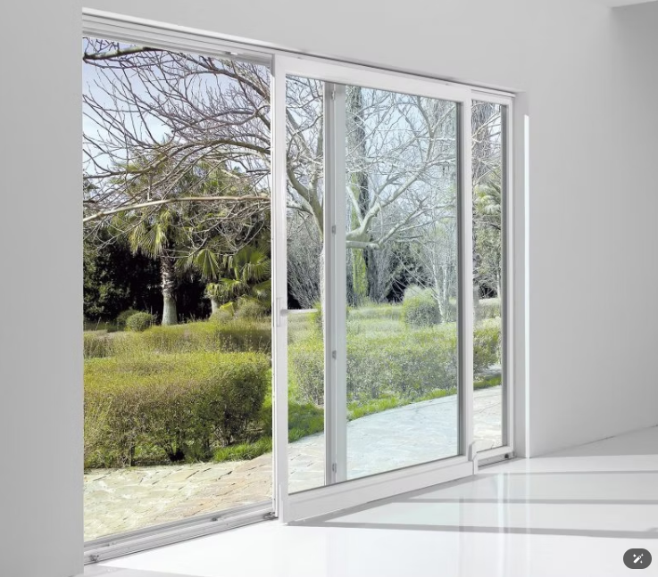 Porte finestre bianche si aprono e si affacciano su un giardino verde con alberi e siepi.