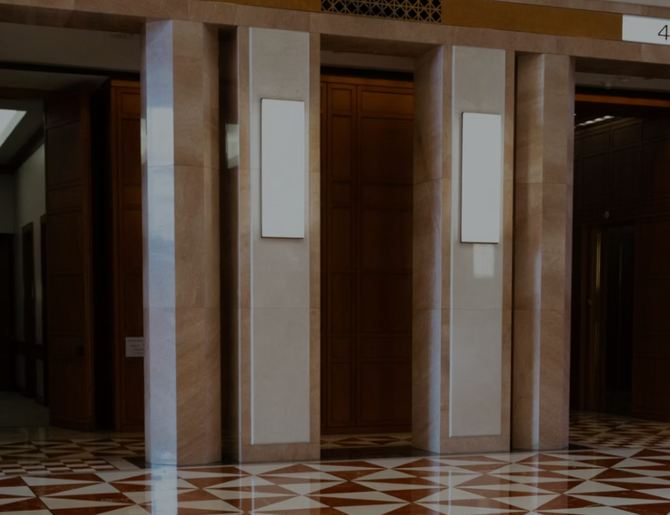 Atrio vuoto con colonne rivestite in legno, pareti beige e pavimento piastrellato con motivi decorativi.