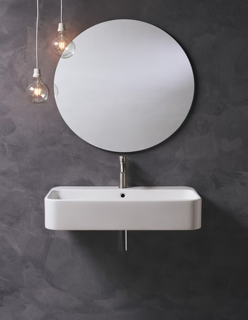 Lavabo da bagno moderno con specchio rotondo e lampade a sospensione su una parete scura.