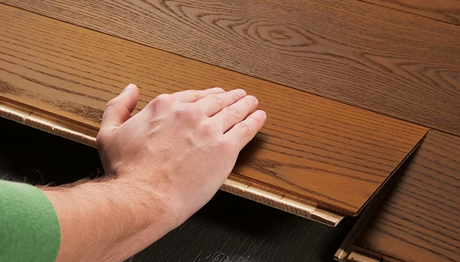 Test manuale di una striscia di transizione per pavimenti in legno con bordo visibilmente sollevato.