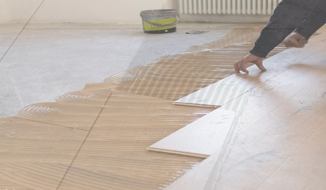 Persona che stende l'adesivo su un pavimento piastrellato con una cazzuola durante l'installazione (작업)