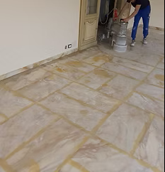 Operai che levigano un pavimento piastrellato in una stanza in fase di ristrutturazione.
