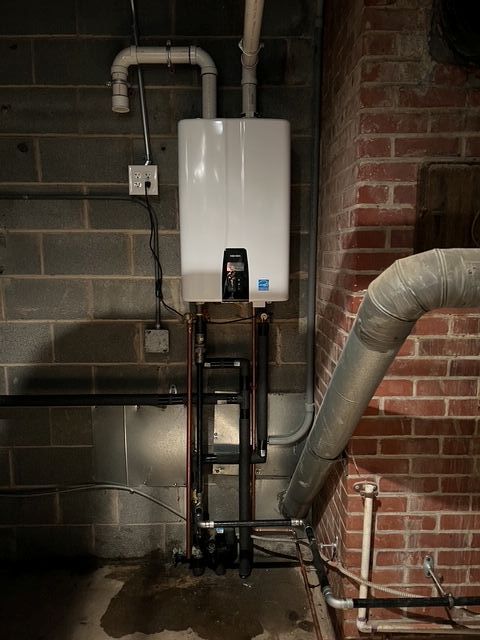 Wall-mounted white boiler with black piping in a brick basement utility room