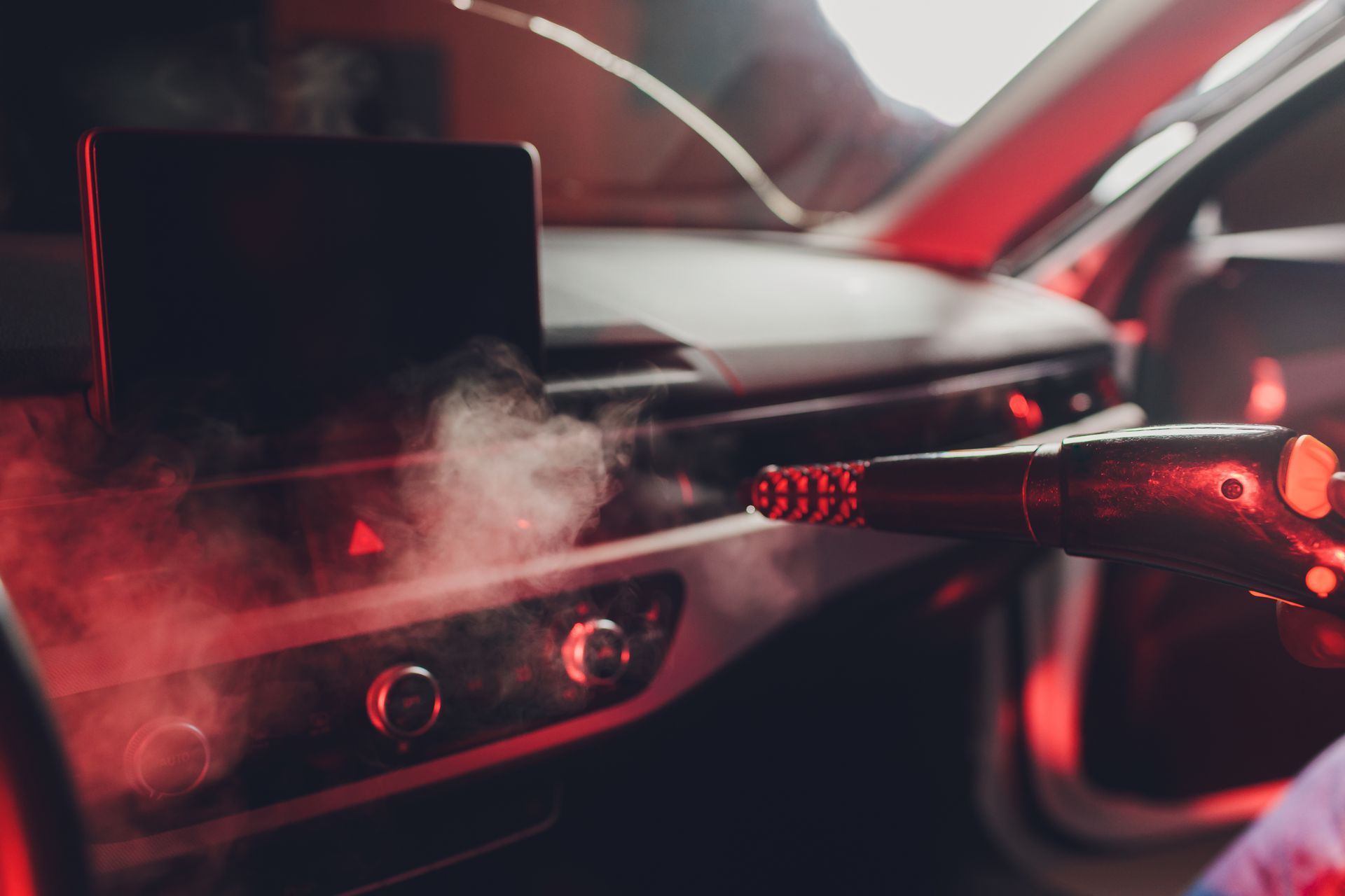 A person is cleaning the interior of a car with a vacuum cleaner.