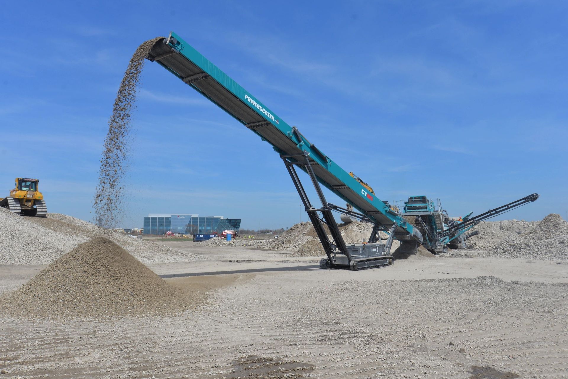 A conveyor belt is pouring gravel into a pile of gravel.