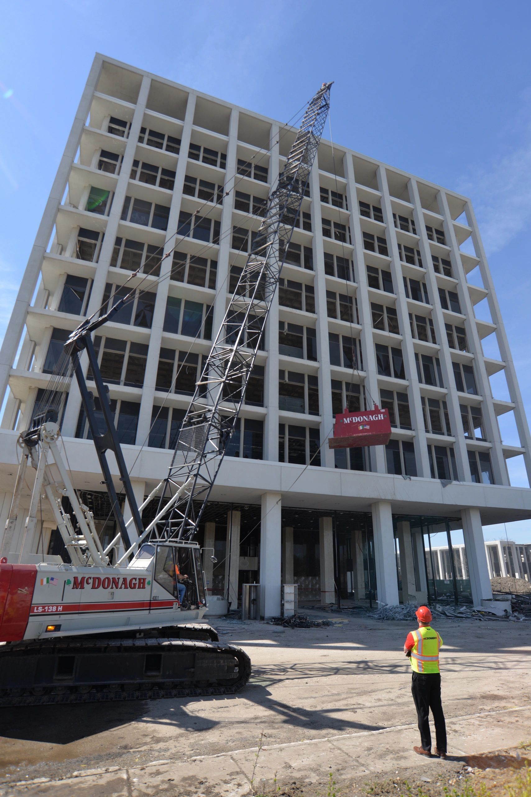 A construction worker is standing in front of a large building under construction.