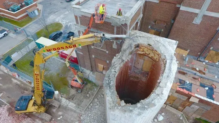 An aerial view of a building being demolished by a crane.