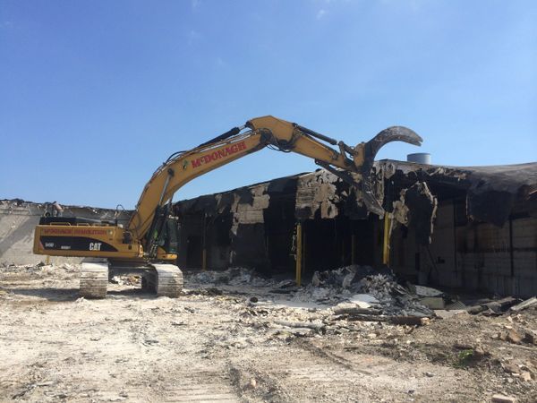 A yellow cat excavator is demolishing a building