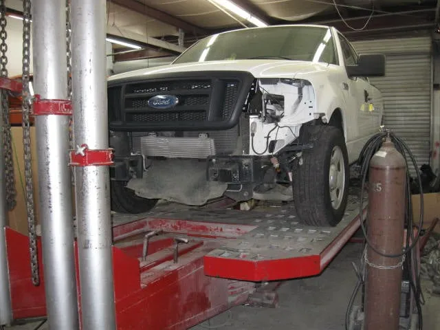 A white ford truck is being worked on in a garage