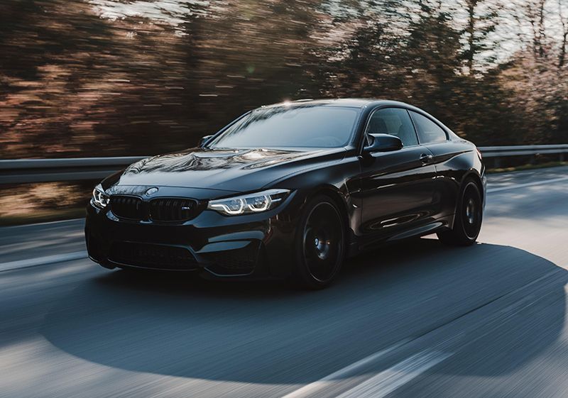 A black bmw m4 is driving down a highway.