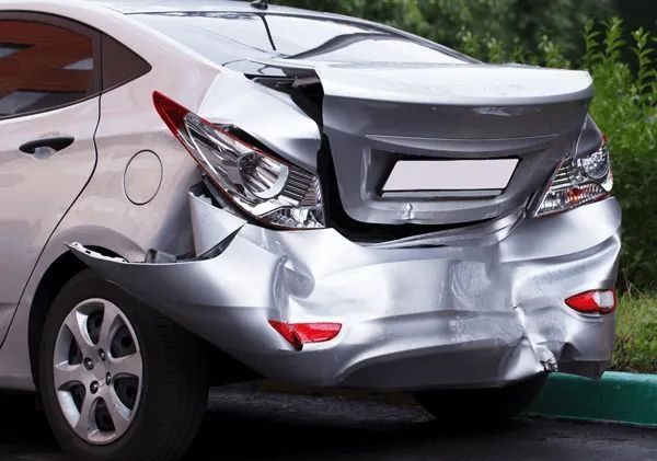 A silver sedan with severe rear-end damage, including a crumpled bumper and a damaged trunk lid.