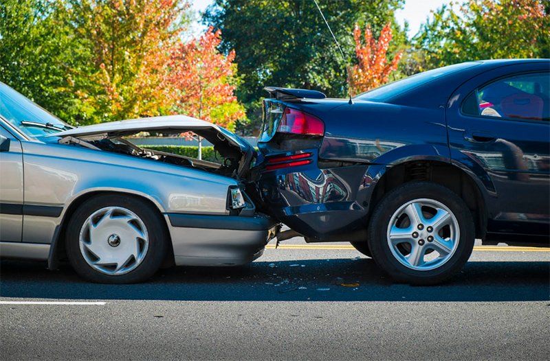 Two cars are involved in a car accident on the side of the road.