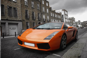 An orange sports car is parked on the side of the road