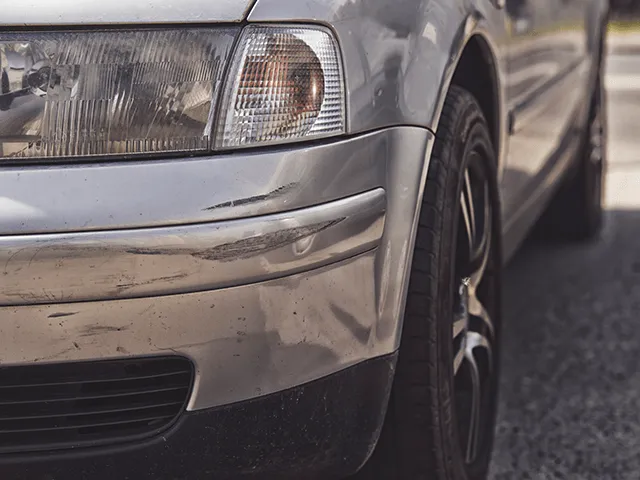 A silver car is parked on the side of the road.
