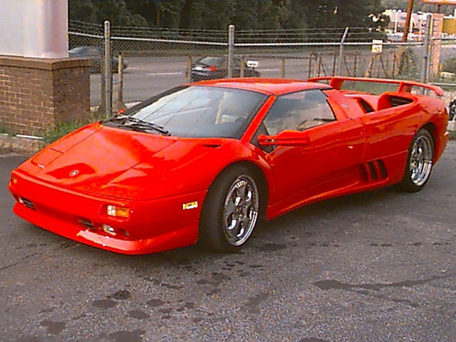 A red sports car is parked in a parking lot
