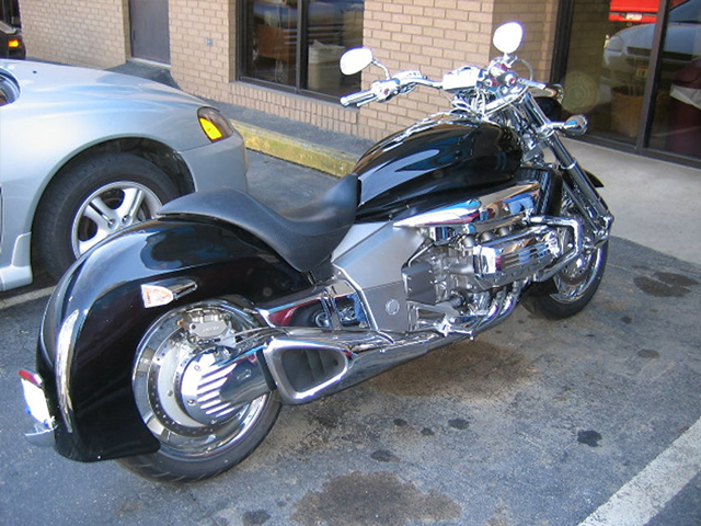A black motorcycle is parked next to a silver car