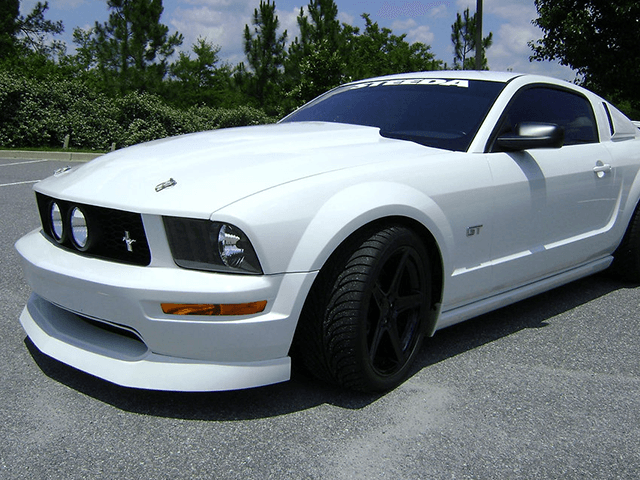 A white mustang is parked in a parking lot