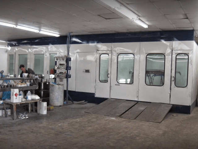A man is working in a paint booth in a garage