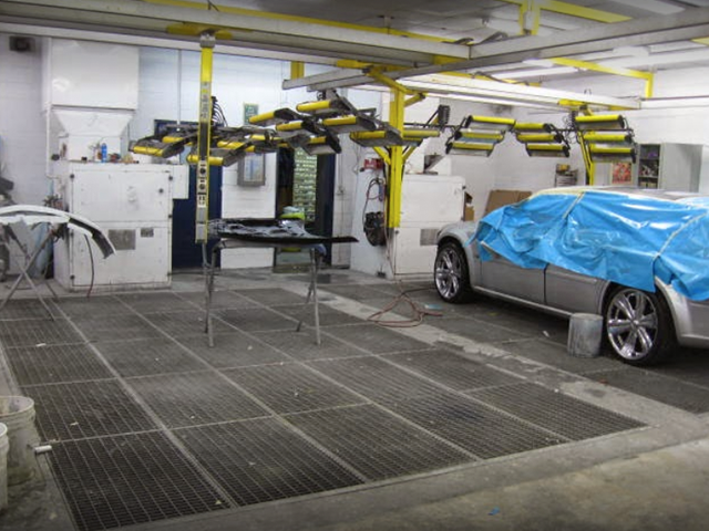 A car is covered in a blue tarp in a garage