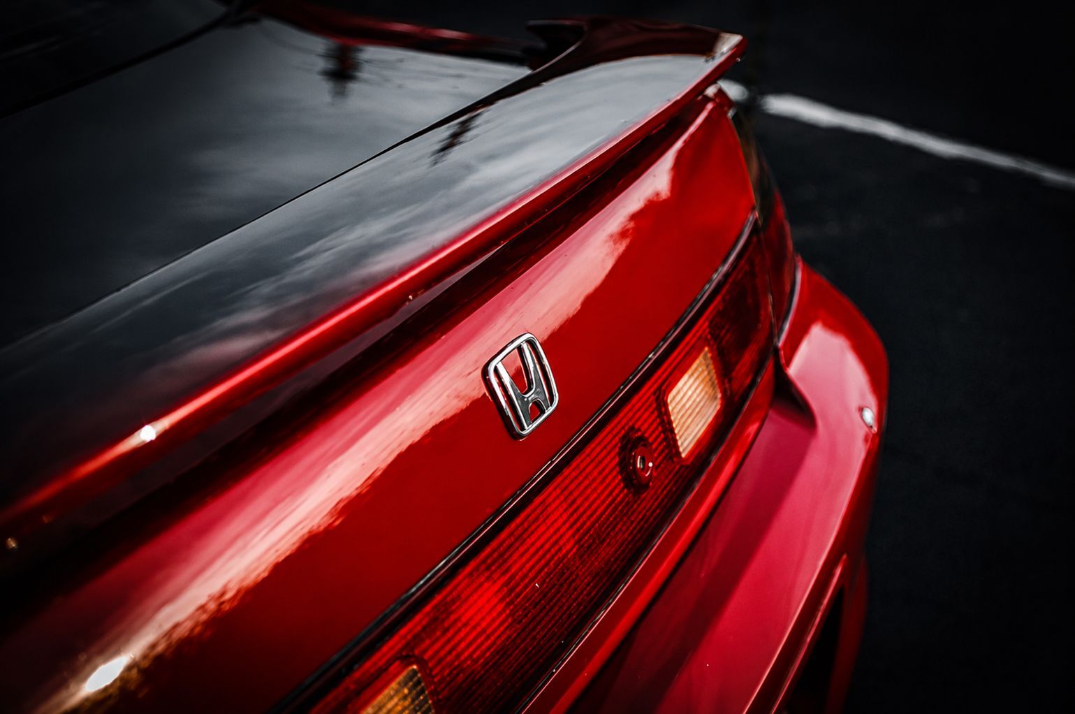 Red Honda car rear in glossy red paint under dramatic lighting