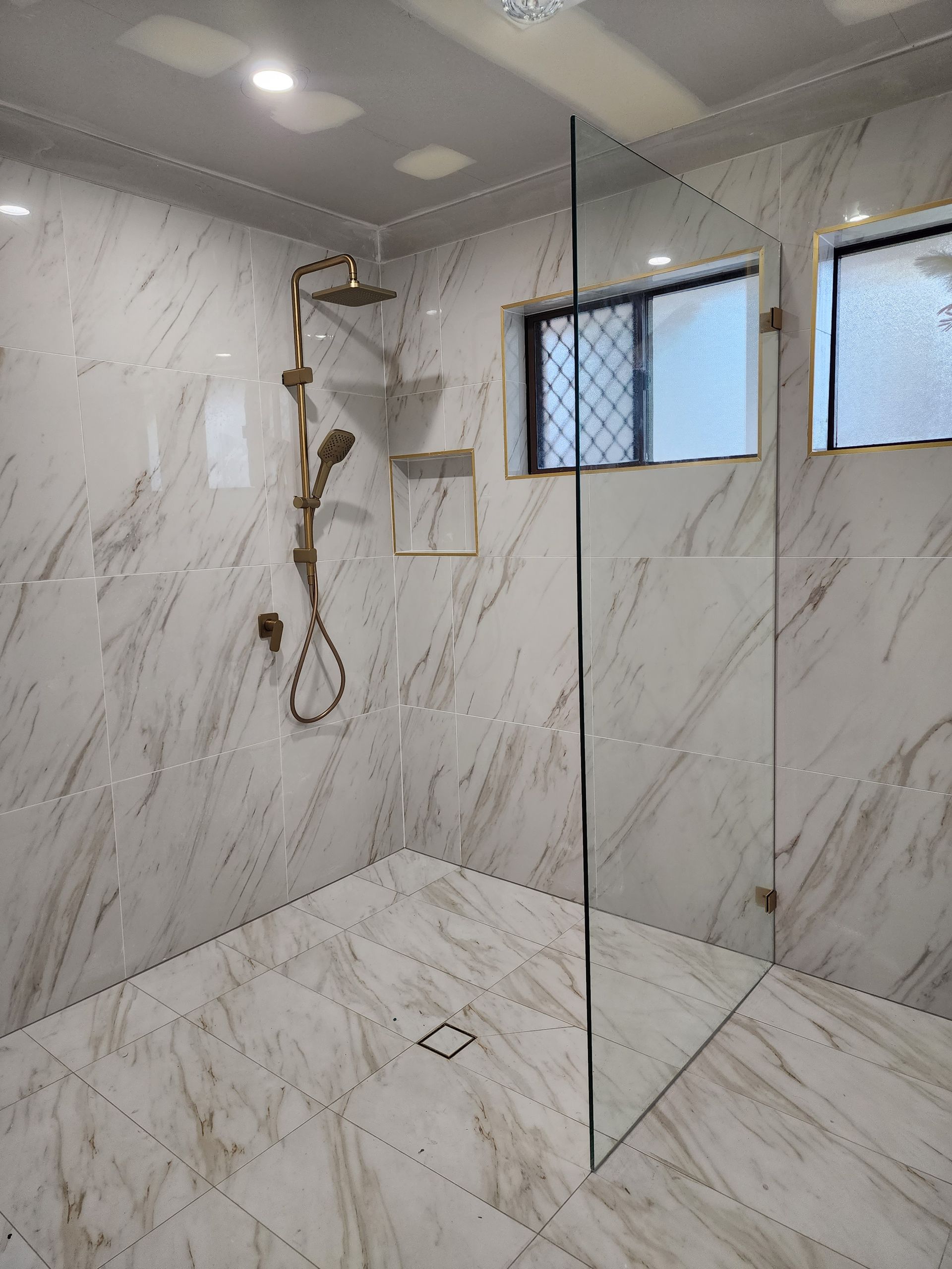 A Bathroom With A Sliding Glass Shower Door And A Sink — Lumba Glass & Glazing In Kincumber, NSW