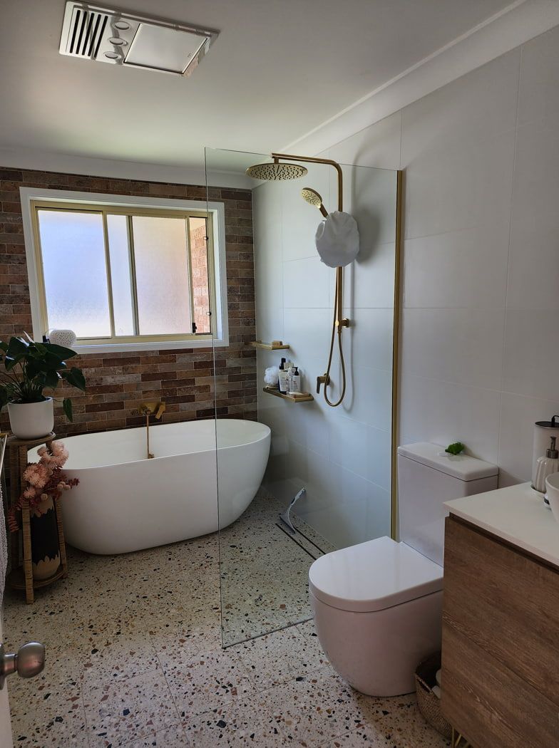 A Bathroom With A Tub, Toilet, Sink And Window — Lumba Glass & Glazing In Kincumber, NSW