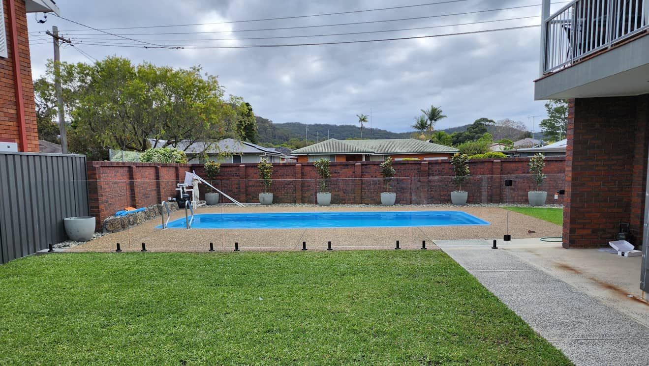 There Is A Large Swimming Pool In The Backyard Of A House — Lumba Glass & Glazing In Kincumber, NSW