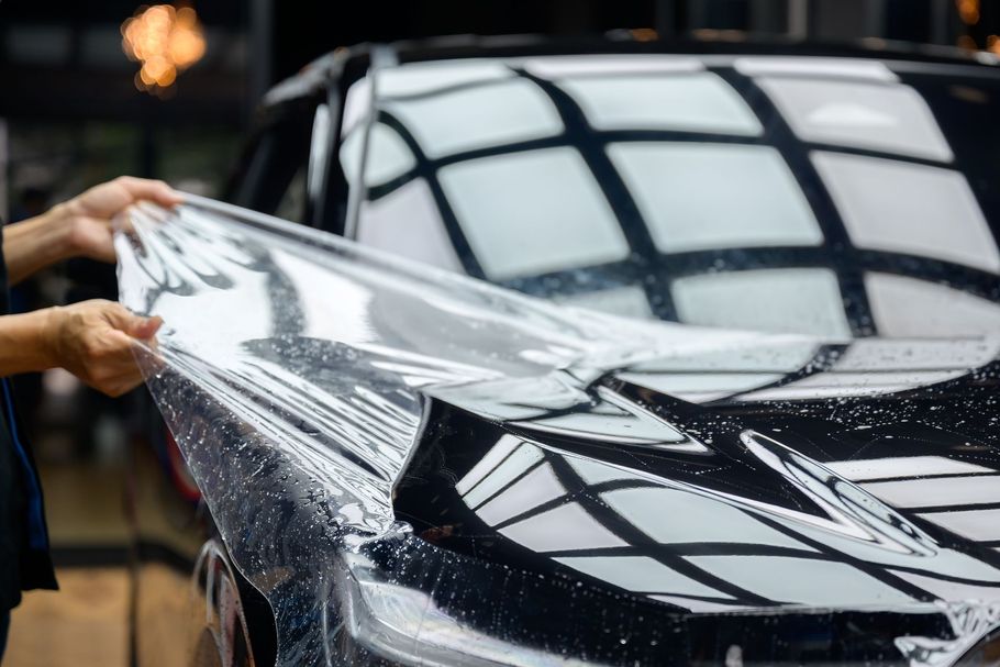 Person inspecting car damage, pointing at a dent on the side panel, writing on a clipboard.