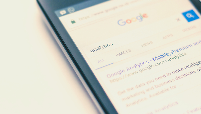 A close up of a cell phone displaying a google search page.
