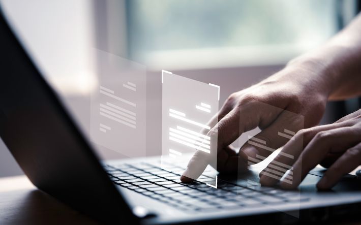 A person is typing on a laptop computer with a graph on the screen.