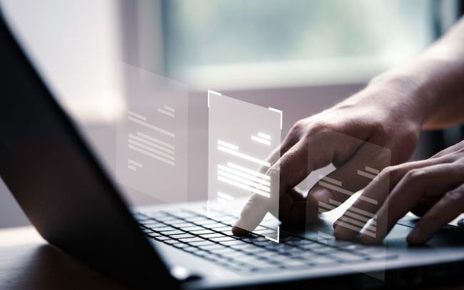 A person is typing on a laptop computer with a graph on the screen.