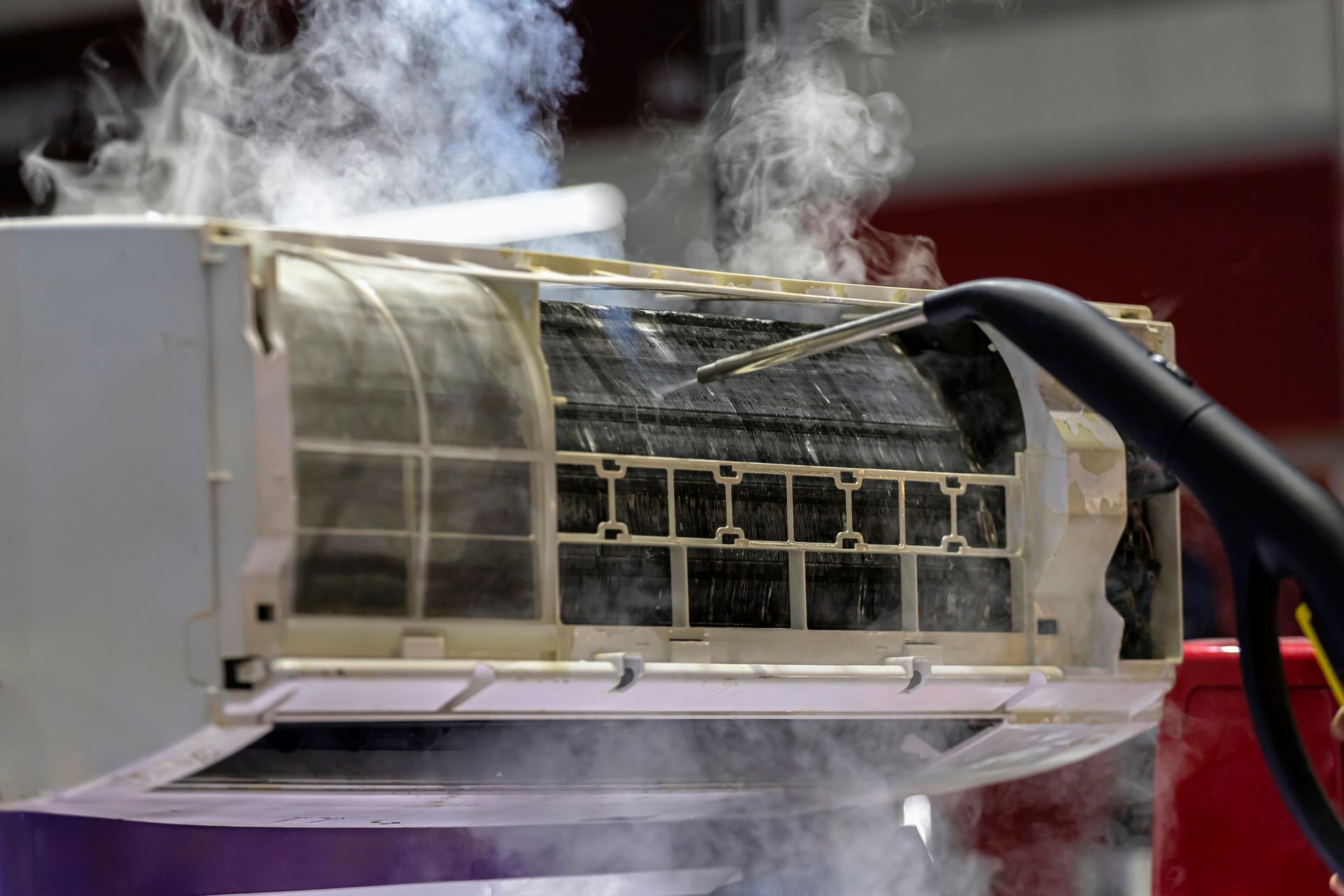 Steam cleaning an air conditioner unit, removing dirt.