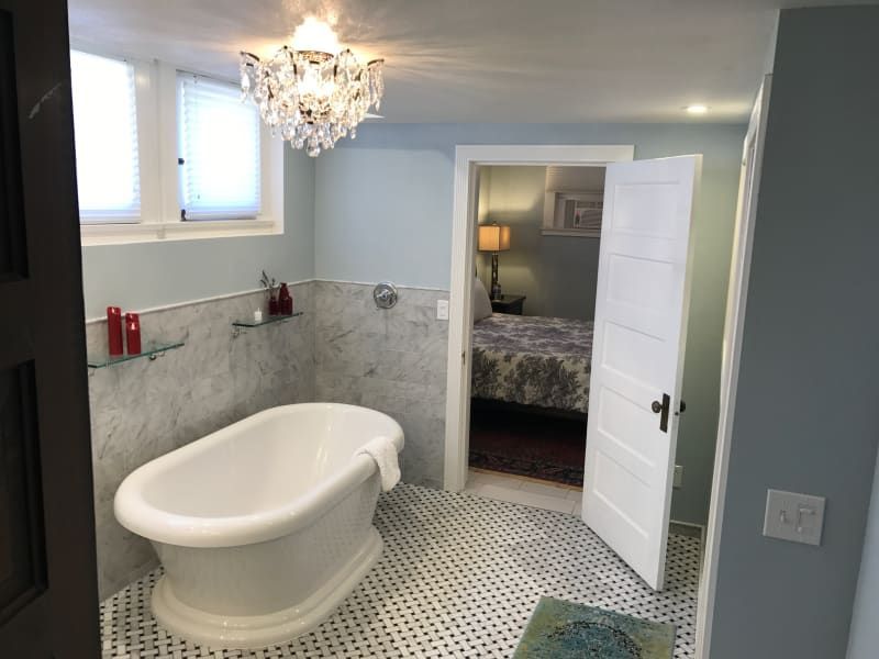 A bathroom with a bathtub and a chandelier hanging from the ceiling.