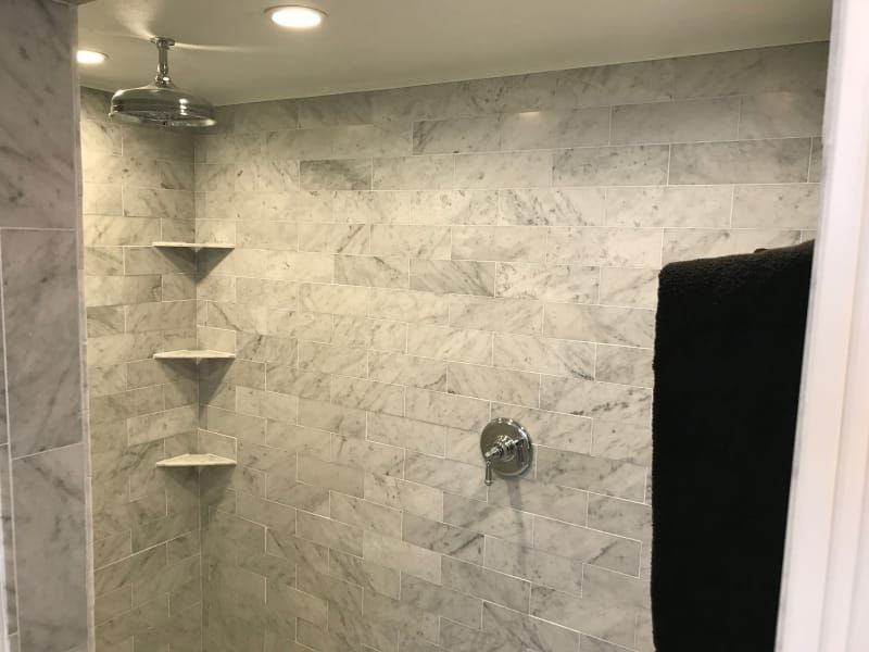 A bathroom with marble tiles and a shower head.
