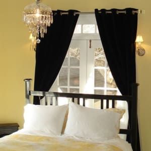 A bedroom with a bed and a window with black curtains