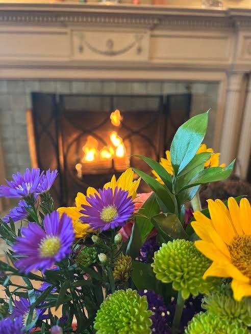 A fireplace with purple and yellow flowers in front of it