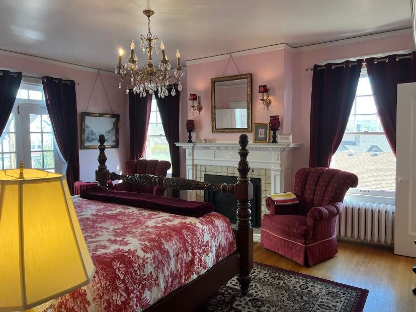 A bedroom with a bed , chair , lamp and fireplace.