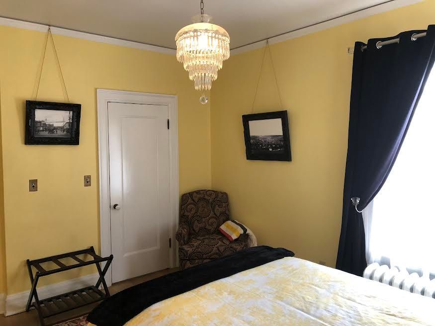 A bedroom with yellow walls and a chandelier hanging from the ceiling