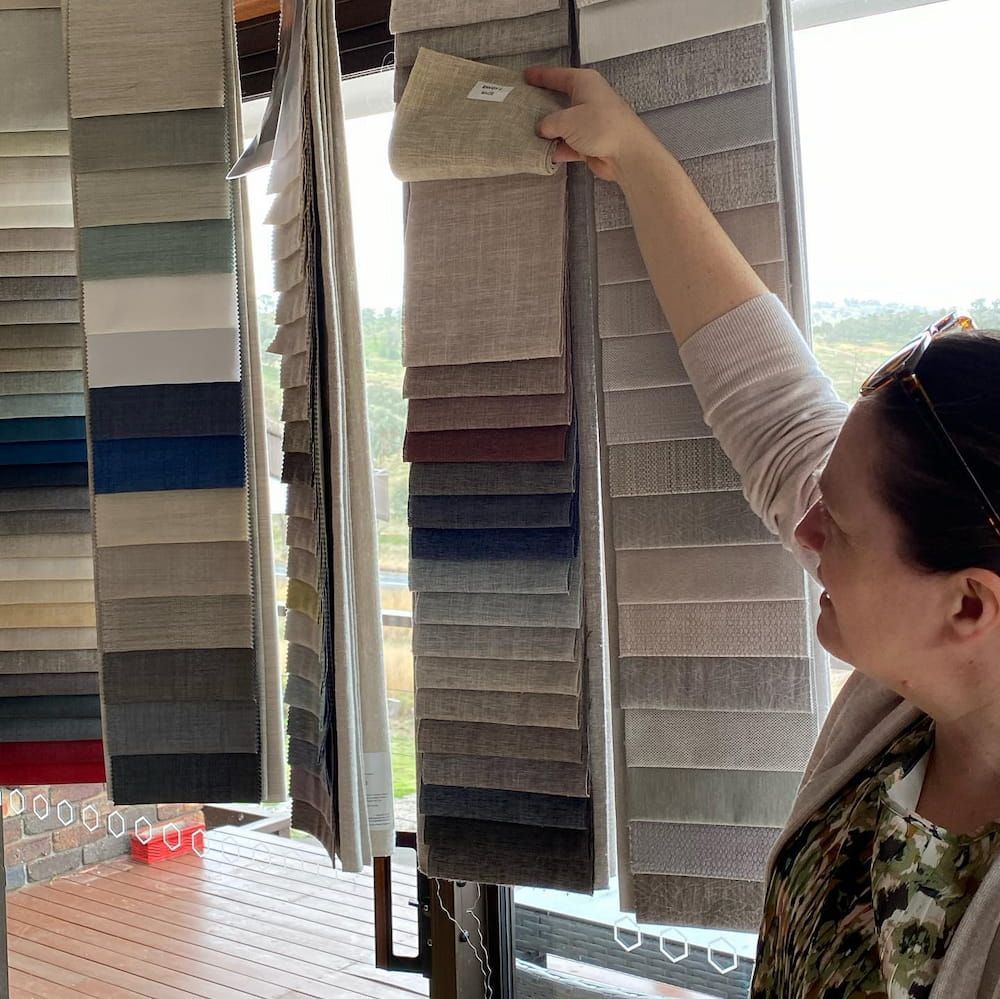 A Woman is Looking at Fabric Samples in a Store — Tamworth Interiors in Tamworth, NSW 