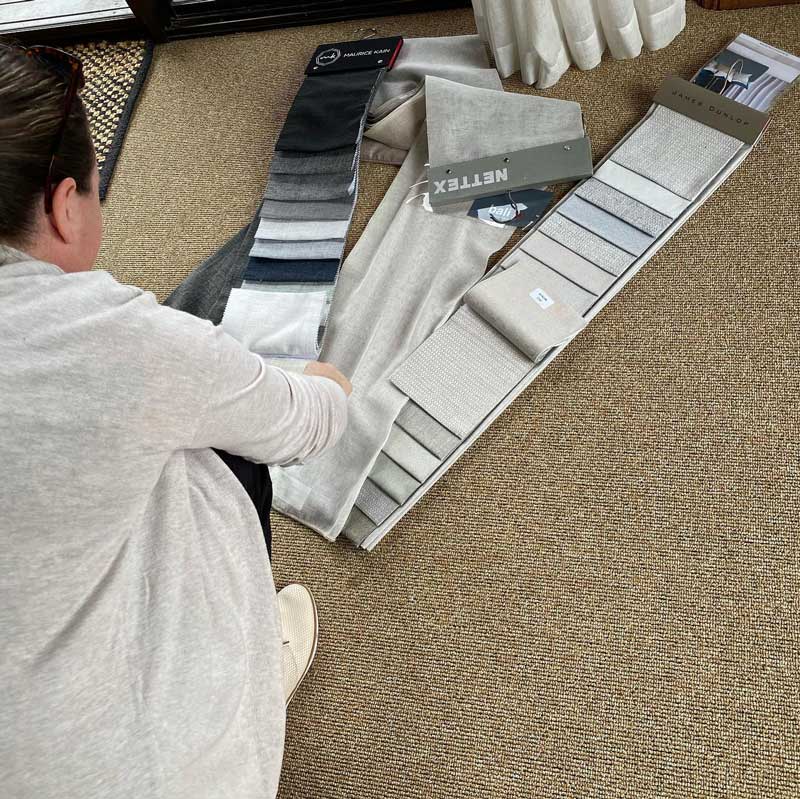 A Woman is Sitting on the Floor Looking at Fabric Samples — Tamworth Interiors in Quirindi, NSW