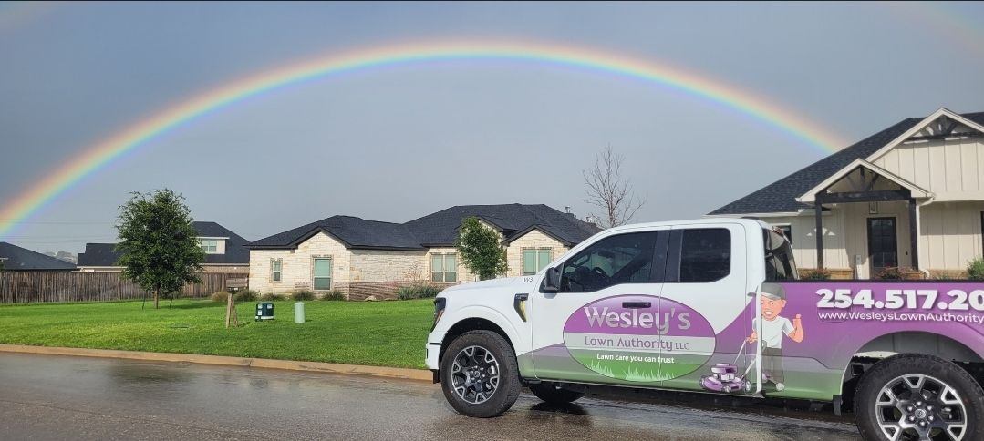 A truck is parked in front of a house with a rainbow in the background.