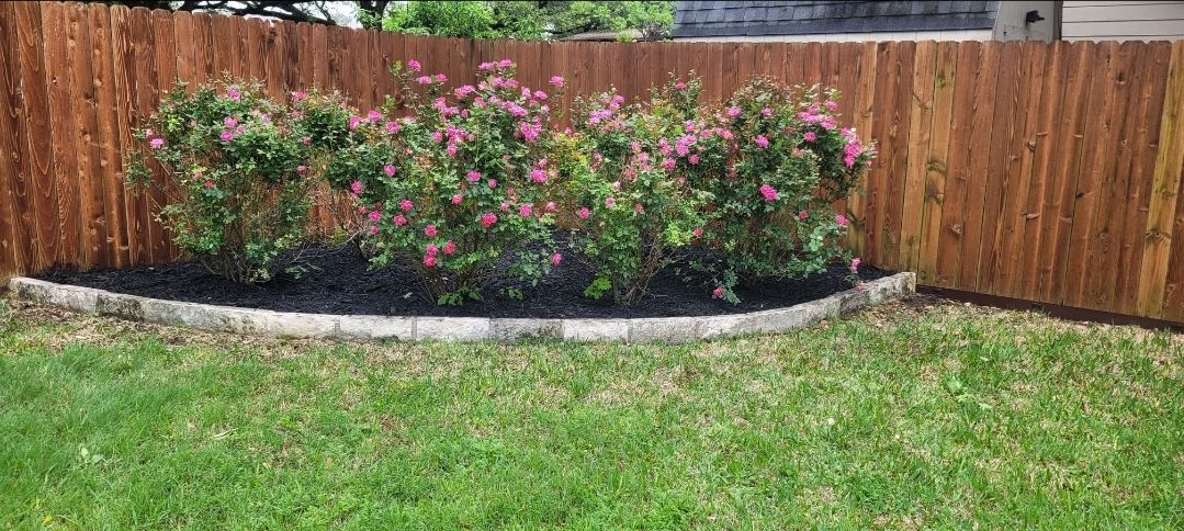 A wooden fence with flowers in front of it in a yard.