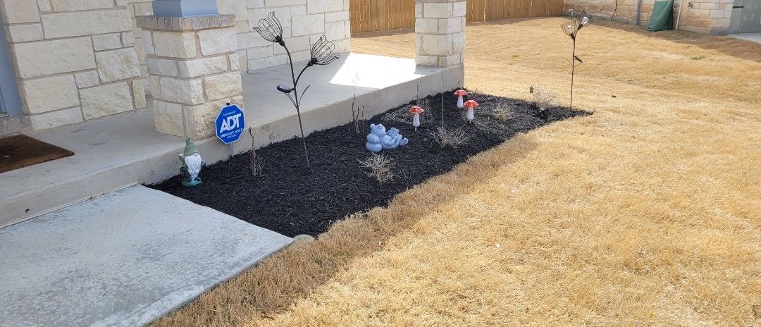 A lawn with a concrete walkway and a gravel area in front of a house.