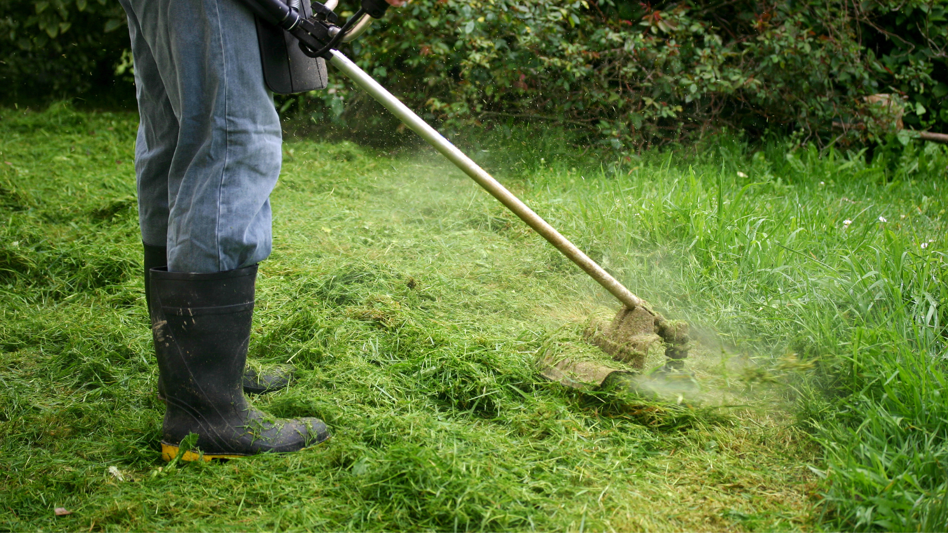 A man is mowing the grass with a lawn mower.