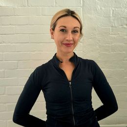 A head-and-shoulders picture of a young women smiling with blonde hair tied back, wearing a black shirt.