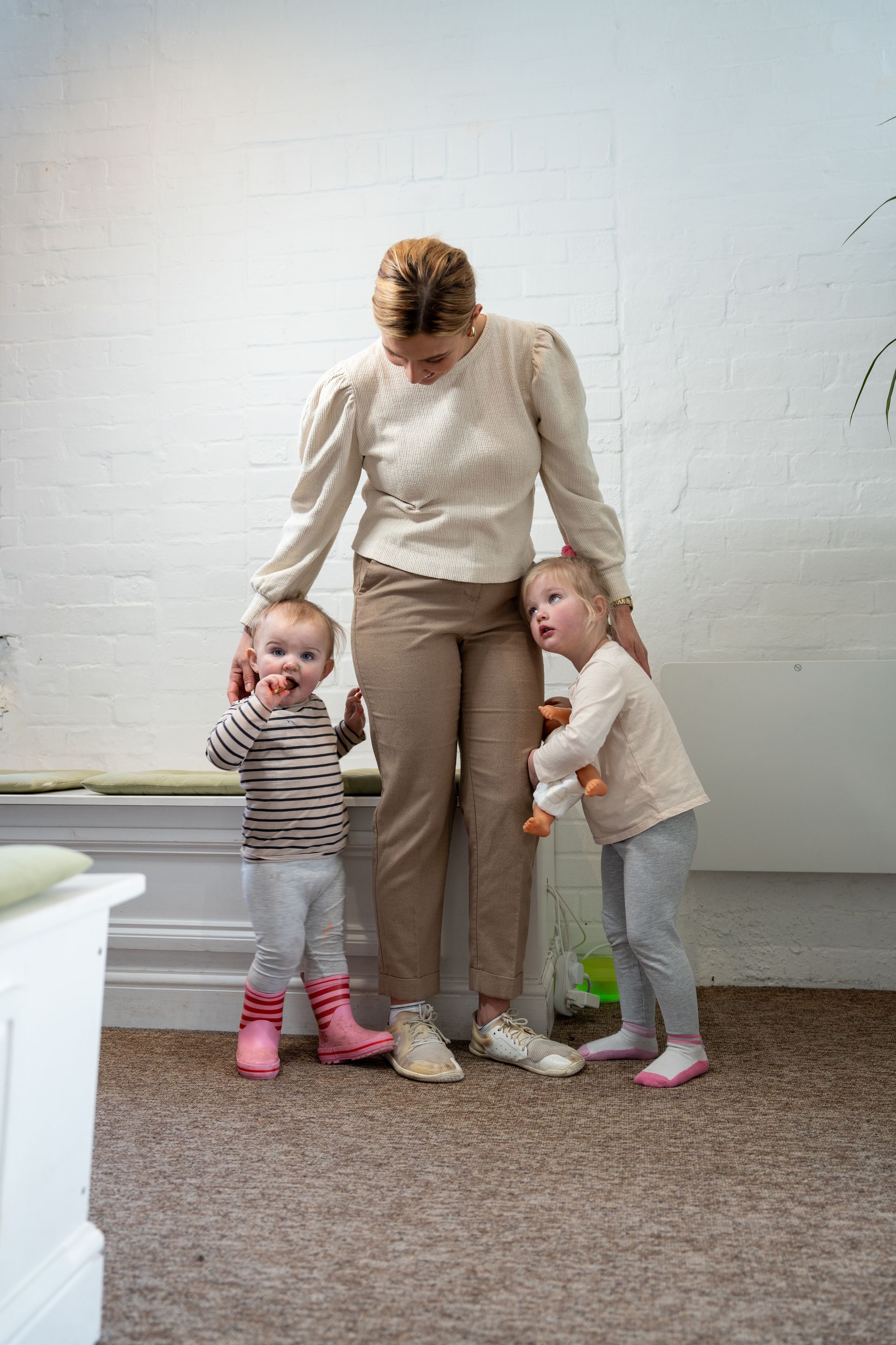 A woman is standing next to two little girls in a living room.