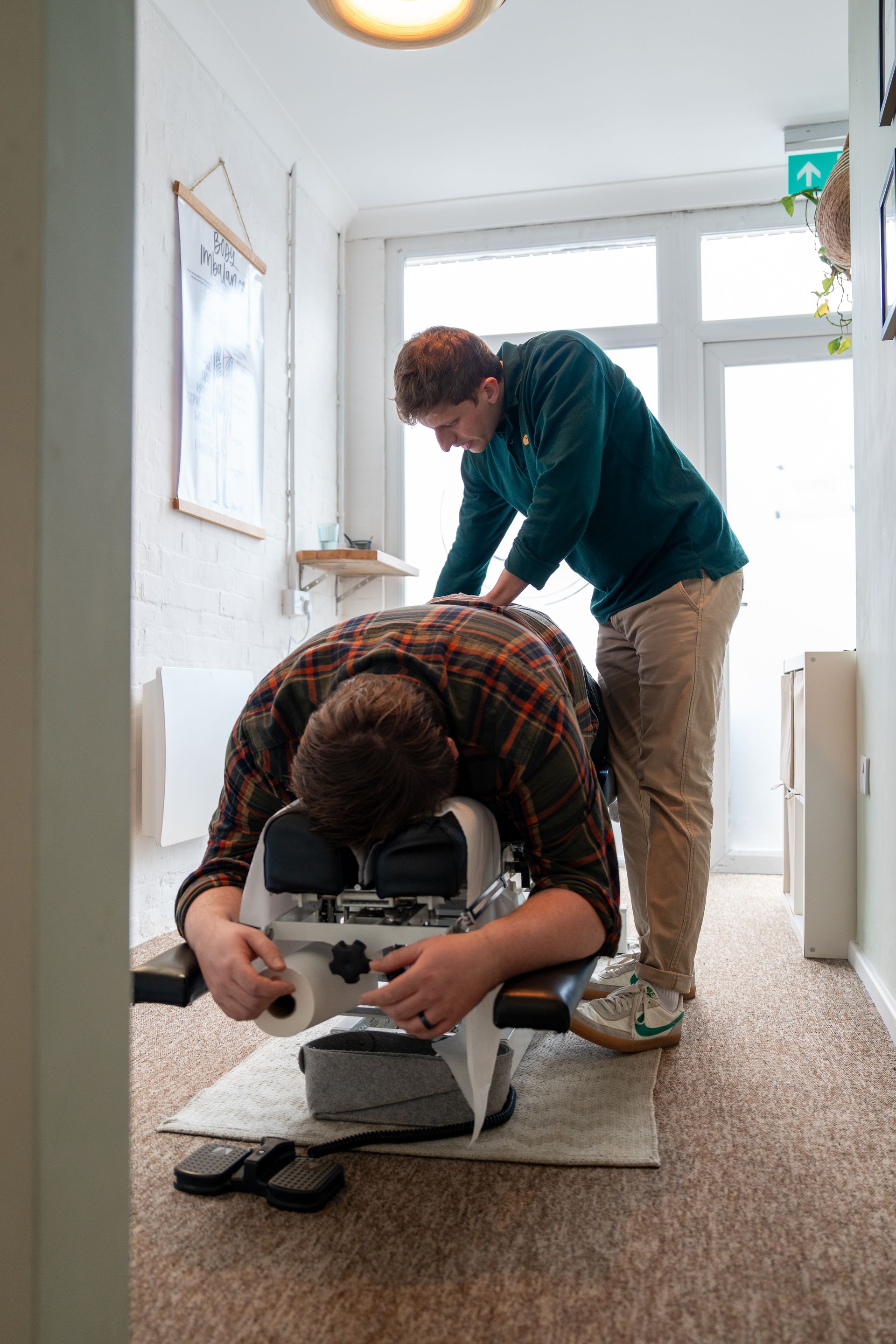 A man is laying on a table while another man works on his back.